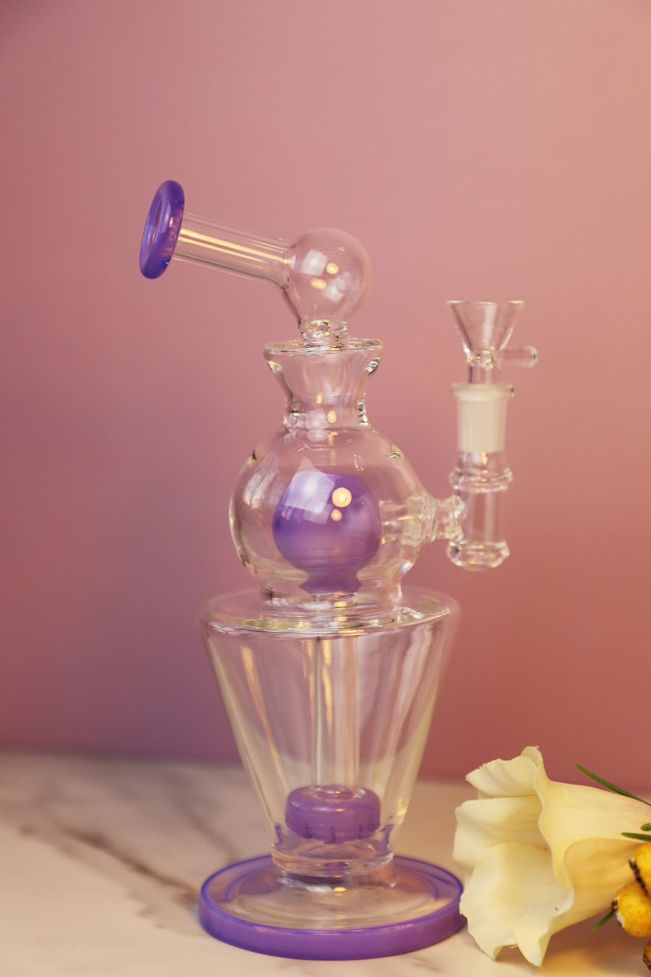 Miniature Glass Bong with Purple Accents and Elegant Design for Discerning Tastes, featuring a sophisticated silhouette with intricate glasswork, suitable for enthusiasts who appreciate the functionality and aesthetics of portable smoking accessories. Its compact form factor and stylish purple detailing make it a chic and discreet choice for personal use