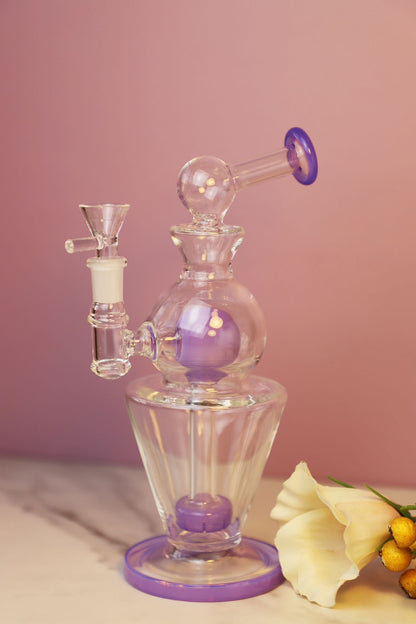 Miniature Glass Bong with Purple Accents and Elegant Design for Discerning Tastes, featuring a sophisticated silhouette with intricate glasswork, suitable for enthusiasts who appreciate the functionality and aesthetics of portable smoking accessories. Its compact form factor and stylish purple detailing make it a chic and discreet choice for personal use